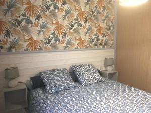 a bedroom with a bed with two pillows and a wallpaper at Appartement 2 pièces près des thermes in Bagnoles de l'Orne