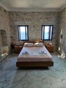 a bedroom with a large bed in a room with windows at Rigas stone tower east Mani 1 in Mína