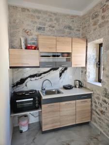 a kitchen with wooden cabinets and a sink at Rigas stone tower east Mani 1 in Mína +14 photos