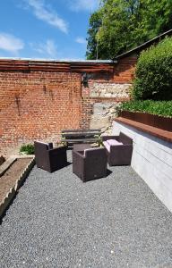 duas cadeiras e um banco em frente a uma parede de tijolos em Maison de ville em Pont-Audemer