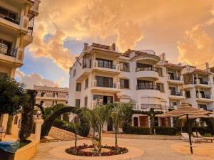 Sharm Hills Resort في شرم الشيخ: مبنى ابيض كبير امامه نخيل