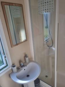 a bathroom with a sink and a shower at Newquay Bay Porth Caravan - 6 berth in Newquay