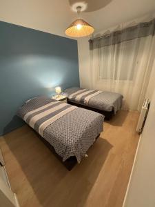 2 Betten in einem Schlafzimmer mit blauer Wand in der Unterkunft Maison landaise, 4 chambres avec jardin, classé 3 étoiles in Biscarrosse