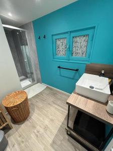 ein Badezimmer mit einem weißen Waschbecken und einer blauen Wand in der Unterkunft Maison landaise, 4 chambres avec jardin, classé 3 étoiles in Biscarrosse