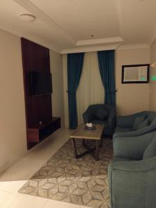uma sala de estar com duas cadeiras azuis e uma mesa de centro em شقق اطلالة أبحر للشقق المخدومة em Jeddah