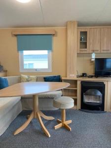 cocina con mesa de madera, mesa y taburete en Newquay Bay Porth Caravan - 8 Berth, en Newquay