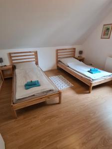two beds in a room with wooden floors at Amselpark in Barkelsby