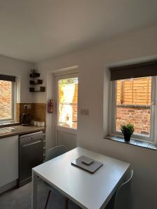 uma cozinha com uma mesa branca e duas janelas em Stylish Ground Floor Apartment Nr Gloucester Docks, by Sauvignon Stays 