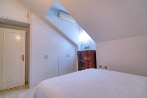 an attic bedroom with a white bed and a window at Dúplex en centro, San Ildefonso in Jaén