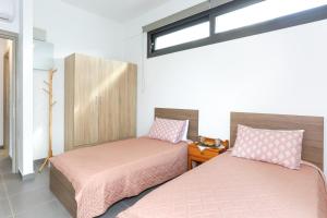 dwa łóżka z różową pościelą w pokoju z oknem w obiekcie Nikolas Villa w mieście Gournes