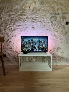 TV en una mesa blanca en una habitación con pared en Appartement dans une vieille ferme bugiste, en Ceyzérieu
