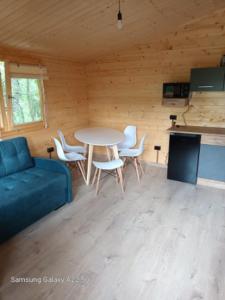 a living room with a blue couch and a table and chairs at UROCZYSKO POD LASEM in Mikoszewo