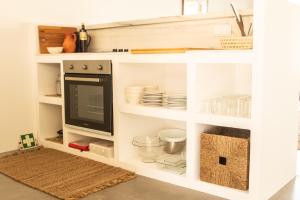 un meuble blanc avec une télévision et de la vaisselle dedans dans l'établissement Vida na Vila, à Vila Nova de Milfontes 16 autres photos