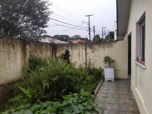 um jardim com uma parede de betão e um pátio em Bairro tranquilo ha dez minutos de carro do centro da cidade em Curitiba