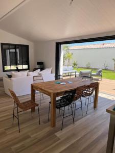 Una sala de estar con una mesa y sillas de madera. en Villa - proche plages/commerces, en Le Bois-Plage-en-Ré