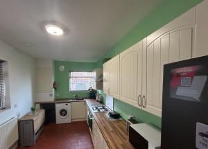 a kitchen with white cabinets and green walls at West Street House in Crewe