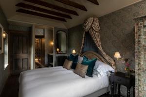 a bedroom with a large white bed with blue pillows at Kildrummy Inn in Kildrummy
