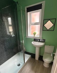 a green bathroom with a sink and a shower at West Street House in Crewe