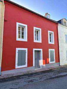 a red and white building on the side of a street at Maison de charme sur le port de Sauzon in Sauzon