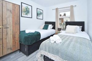 Un dormitorio con dos camas con toallas encima. en Myrtle House - By Sigma Stays, en Crewe