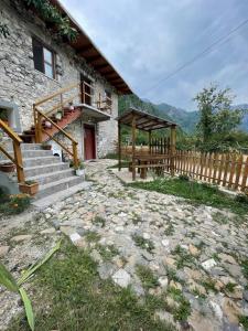 una casa in pietra con una scala in legno e un portico di GUEST HOUSE “ Center Theth “ a Theth