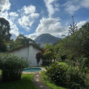 a swimming pool in a yard with a mountain in the background at Hostel 040 in Itaipava