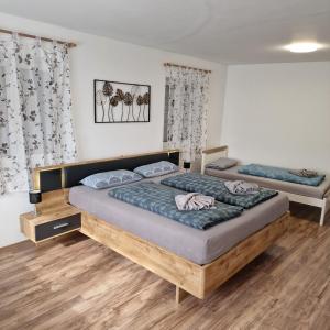 two beds in a room with wooden floors and curtains at Apartment da Luiz Salvatore in Wurmlingen