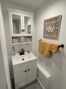 Baño blanco con lavabo y espejo en Basement Bliss: Cozy Getaway, en Cheyenne
