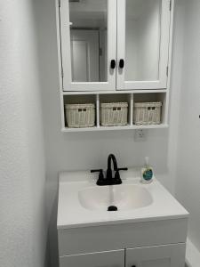 a white bathroom sink with a mirror and baskets at Basement Bliss: Cozy Getaway in Cheyenne
