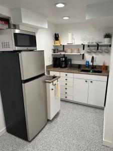 a kitchen with a black refrigerator and white cabinets at Basement Bliss: Cozy Getaway in Cheyenne