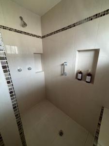 a white bathroom with a shower with a mirror at Casa Macfarland Boutique in Ensenada