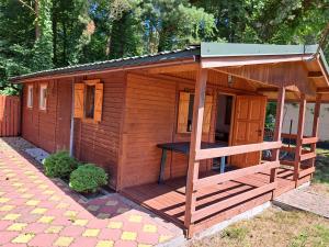 een klein houten huisje met een veranda op een patio bij Nadmorska Pieredyszka in Junoszyno