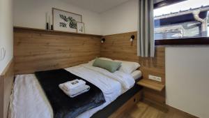 a small bed in a room with a wooden wall at HIŠKA TIBAUT 122 vključene kopalne karte in Veržej