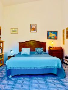 a bedroom with a large bed with a blue bedspread at Montalbano House. Be our guest. in Sciacca
