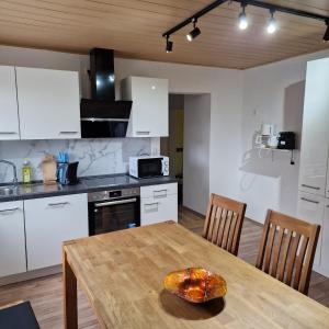 a kitchen with a wooden table and a kitchen with white cabinets at Apartment da Luiz Salvatore in Wurmlingen