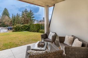 een patio met rieten stoelen en een tafel en uitzicht op een tuin bij Well-Home Apartments Velden Top1 in Velden am Wörthersee