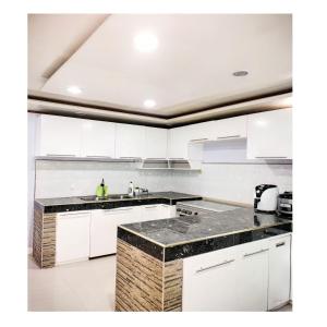 cocina con armarios blancos y encimeras de granito en Rianne's transient house, en Puerto Princesa City