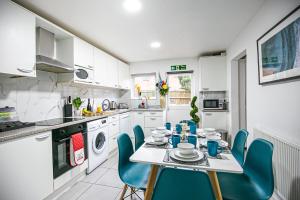 a kitchen with a table and blue chairs in it at Oldbrook House, MK City Center, Large Groups. in Milton Keynes