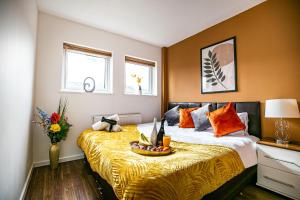 a bedroom with a large bed with a yellow blanket at Oldbrook House, MK City Center, Large Groups. in Milton Keynes