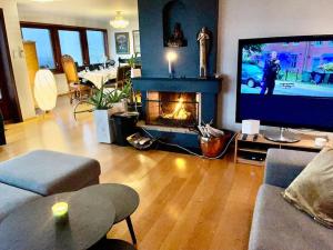 a living room with a fireplace and a tv at Villa med panoramautsikt, stor uteplass og 100 m fra badestrand in Bergen
