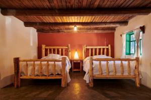two beds in a room with a red wall at Parque Cueva de los Leones in Creel +7 photos