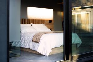 a bed with white sheets and pillows is seen through a window at LA TIERRUCA HOMES in Barcenaciones +17 photos