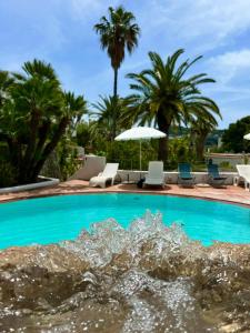 una piscina con sillas, sombrillas y palmeras en Paco Residence Benessere & Relax en Ischia