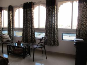 ein Wohnzimmer mit Fenstern sowie einem Tisch und Stühlen in der Unterkunft Devi Vilas Guest House in Udaipur