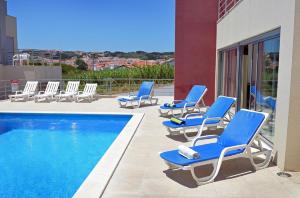 a group of blue lounge chairs next to a swimming pool at Foz Ocean Retreat in Foz do Arelho