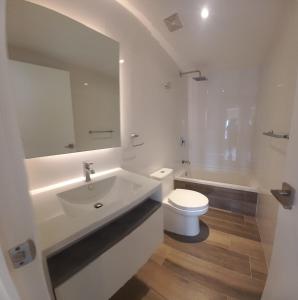 Baño blanco con lavabo y aseo en Apartamento 2 Habitaciones, Edificio Airali, Zona 10, Napoles en Guatemala