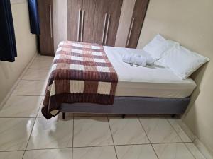 a small bed with a blanket on top of it at Casa de hóspedes em Capão Bonito c/ Wi-Fi in Capão Bonito