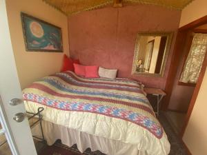 1 dormitorio con 1 cama con un edredón colorido en Artsy Cabin on Organic Farm, en Naalehu
