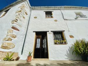 um edifício branco com uma porta e duas janelas em CasaBenadalid. Casa rural con piscina. em Benadalid