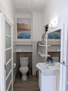 a white bathroom with a toilet and a sink at Above the Sea in Fish hoek